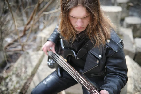 Guitarrista de rock nos degraus. Um músico com uma guitarra baixo em um — Fotografia de Stock