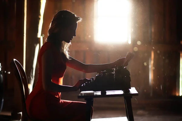 Una chica con estampados de estilo retro en una vieja máquina de escribir — Foto de Stock