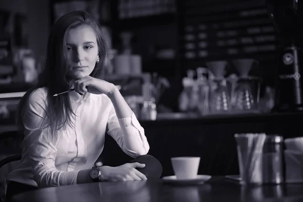 여자는 카페에서 커피를 마시고 있다. 여자는 아침을 먹고는 — 스톡 사진