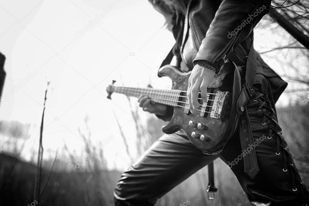 Rock guitarist outdoor. A musician with a bass guitar in a leath