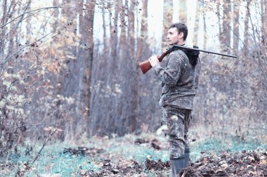 Kamuflaj ve bir sp üzerinde bir ormanda bir av tüfeği ile bir adam