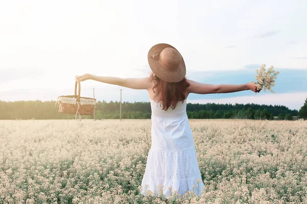 Chica en vestido blanco en un campo de flores amarillas floreciendo — Foto de Stock