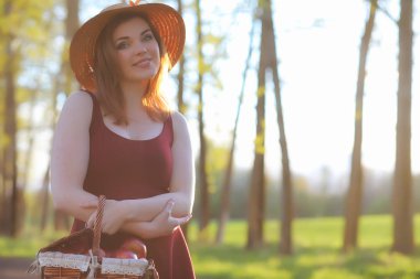 Parkta bir yürüyüş üzerinde şapkalı bir kız. Bir kızla bir sepet yürüyüş