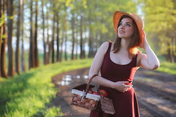 A girl in a hat on a walk in the park. A girl with a basket walk