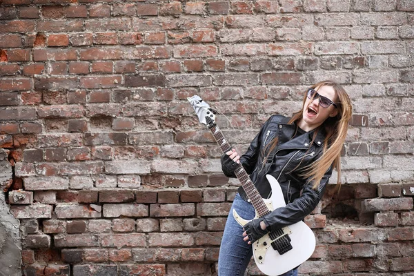 Ένα κορίτσι μουσικός βράχου σε ένα δερμάτινο σακάκι με μια κιθάρα — Φωτογραφία Αρχείου