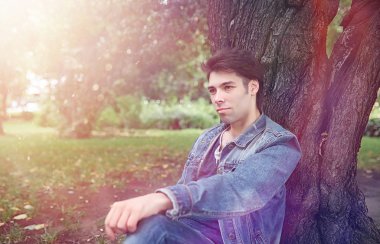 Genç bir adam öğle yemeği zamanında parkta yürür. Bir adam yürüyüşe çıktı. 