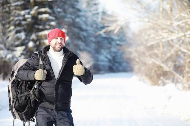Bir adam sırt çantasıyla seyahat eder. Ormanda kış yürüyüşü. Touris