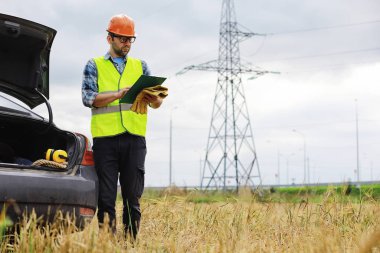 Kasklı ve üniformalı bir adam, sahada bir elektrikçi. Profesör.
