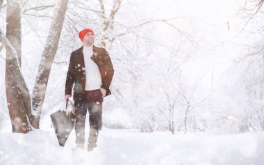 Parkta yürüyen bir adam. Genç adam kışın karla kaplı