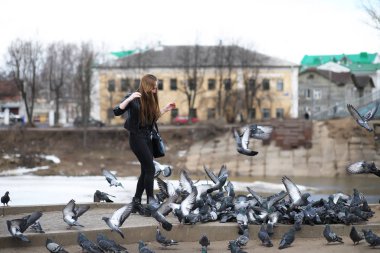 Parkta yürüyen bir kız ve bir güvercin sürüsü
