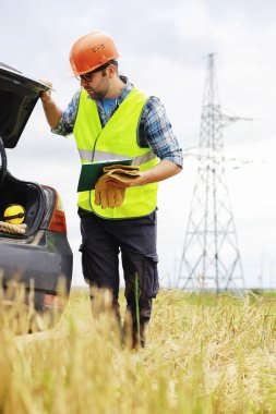 Kasklı ve üniformalı bir adam, sahada bir elektrikçi. Profesör.