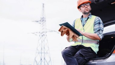 Kasklı ve üniformalı bir adam, sahada bir elektrikçi. Profesör.