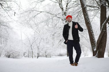 Parkta yürüyen bir adam. Genç adam kışın karla kaplı