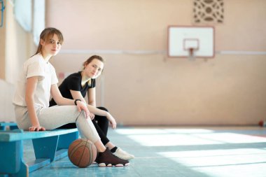 kız öğrenciler spor salonunda basketbol oynuyorlar. 