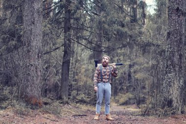 Büyük bir balta ile sakallı bir oduncu ağaç felling önce inceler