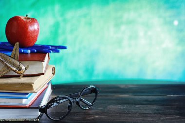 Eğitim konsepti. Bir yığın ders kitabı ve masanın üstünde bir kitap.