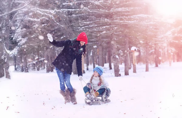 En vintersaga, en ung mamma och hennes dotter rida en släde — Stockfoto