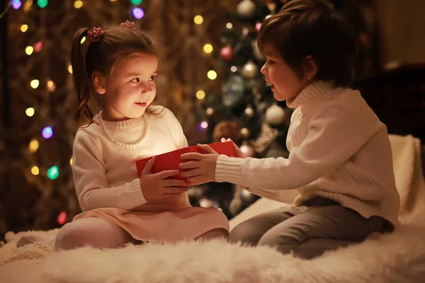 Rodziny w Wigilię Bożego Narodzenia przy kominku. Dzieci Boże Narodzenie prezenty otwarcia — Zdjęcie stockowe