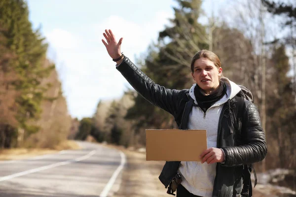 Ένας νεαρός άνδρας είναι hitchhiking γύρω από τη χώρα. Ο άνθρωπος προσπαθεί — Φωτογραφία Αρχείου