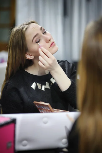 A young girl does make-up in a beauty salon. The girl in front o — Stock Photo, Image