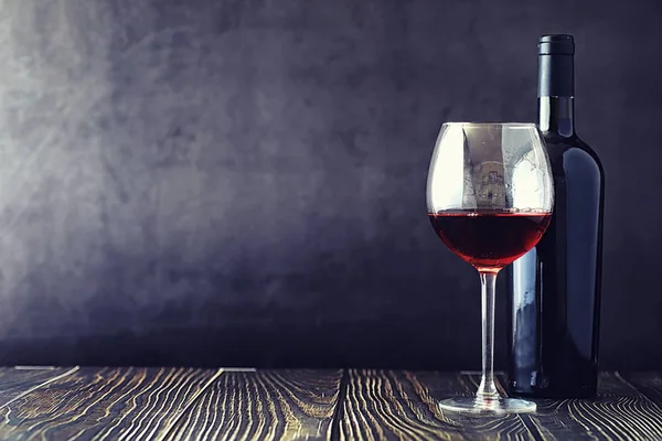 Una copa de vino tinto seco sobre la mesa. Botella oscura y vidrio de w — Foto de Stock