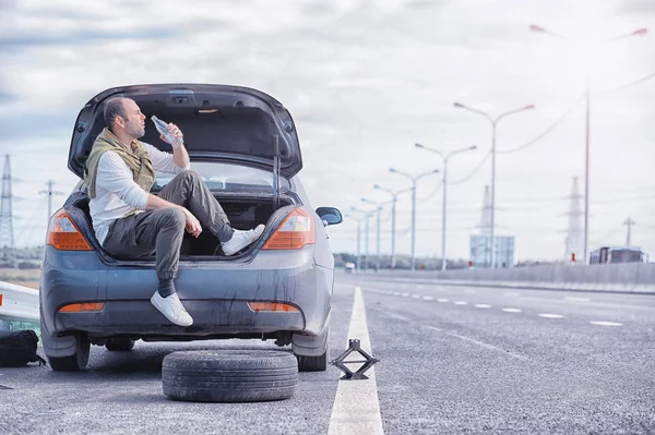 Replacing the wheel of a car on the road. A man doing tire work — Stock Photo, Image