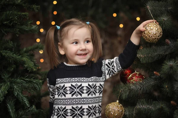 A little child by the New Year tree. Children decorate the Chris — Stock Photo, Image