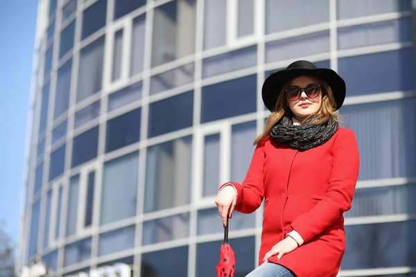 Mooi meisje op een wandeling in de rode jas in de stad — Stockfoto