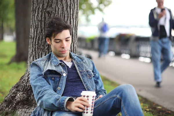 A young man walks in the park at lunch time. A man is on a walk