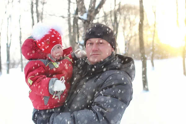 Father with daughter in the park in winter snow blizzard