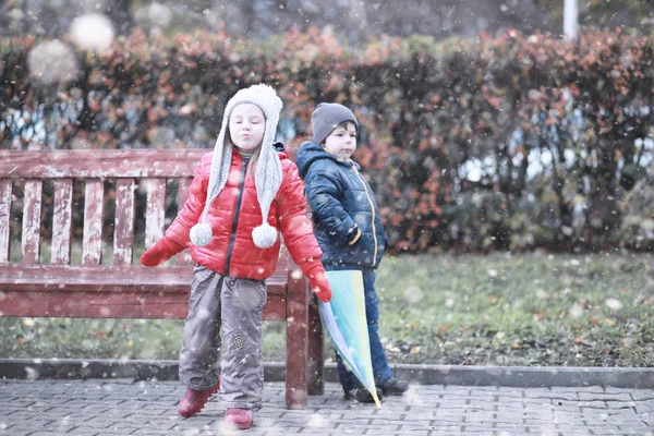 Dzieci chodzą w parku pierwszy śnieg — Zdjęcie stockowe