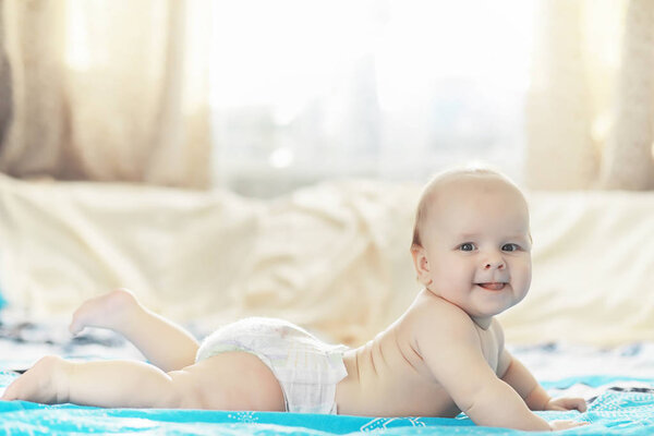 A newborn baby is lying on a soft bed.