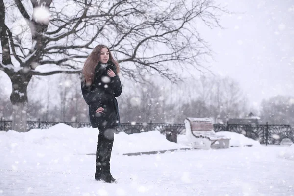 Menina em um parque de inverno na queda de neve — Fotografia de Stock