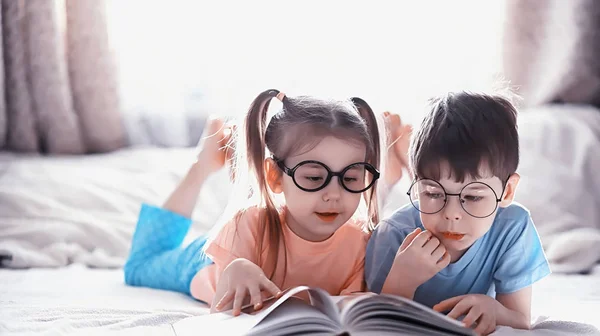 Kinderen liggen op het bed naast de pasgeboren baby, zusje. — Stockfoto