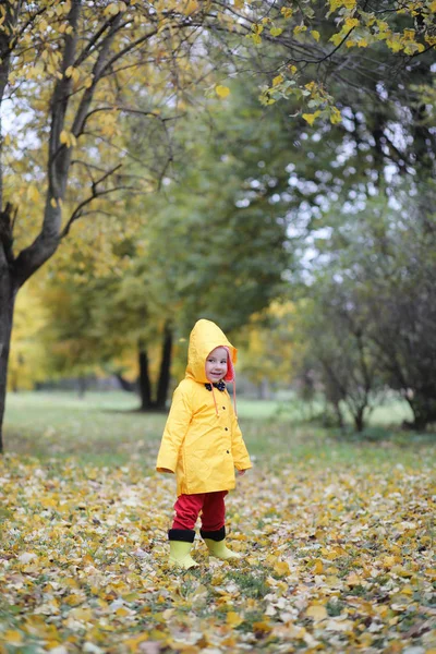 Ett barn i en regnrock för en promenad utanför — Stockfoto