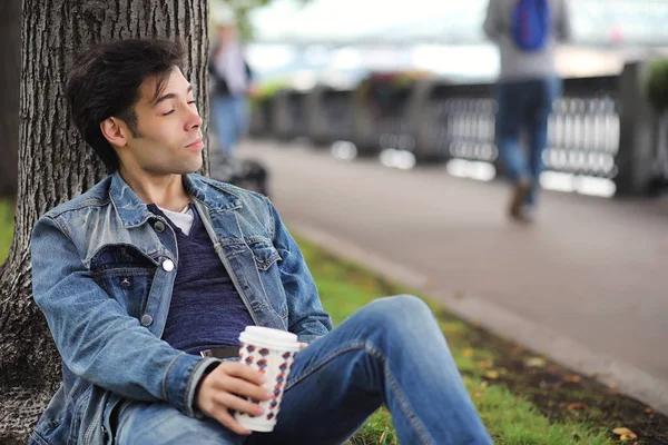 A young man walks in the park at lunch time. A man is on a walk