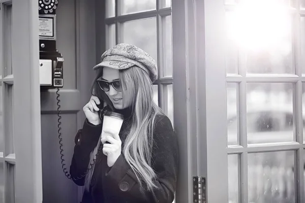 Menina bonita em uma cabine telefônica. A menina está falando no th — Fotografia de Stock