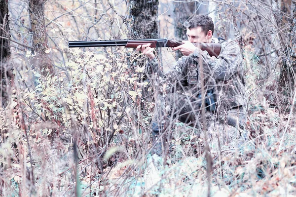 A man in camouflage and with a hunting rifle in a forest on a sp — Stock Photo, Image