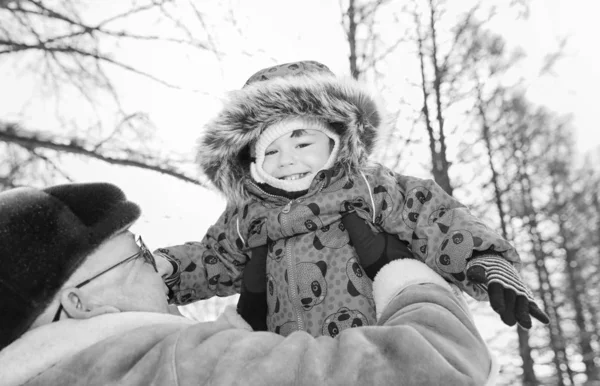 Foto en blanco y negro de los padres sosteniendo al niño en las manos en invierno p — Foto de Stock