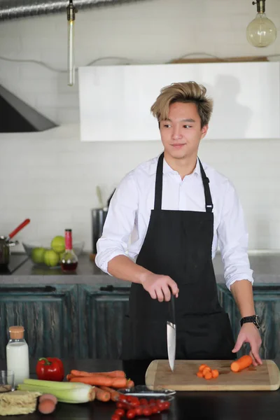 Asian cook in the kitchen prepares food in a cook suit