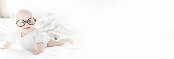 Un bebé recién nacido está acostado en una cama blanda con gafas . — Foto de Stock