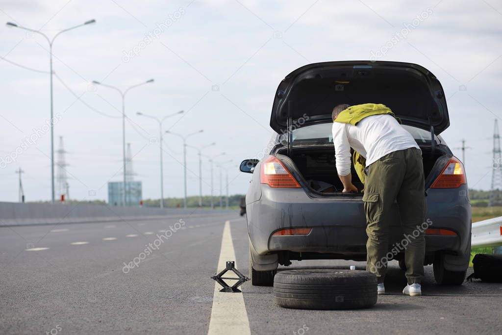 Replacing the wheel of a car on the road. A man doing tire work 