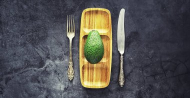 Avokado yemek tarifleri. Olgun yeşil avokado ahşap bir kesim üzerinde 