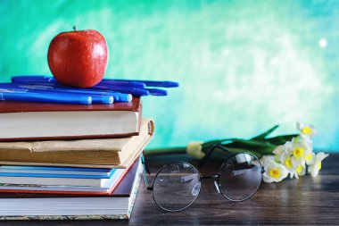 Eğitim konsepti. Bir yığın ders kitabı ve masanın üstünde bir kitap.