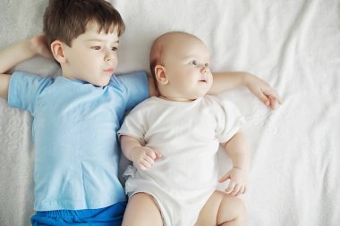 Çocuklar yeni doğan bebeğin yanındaki yatakta yatıyor, küçük kız kardeş..