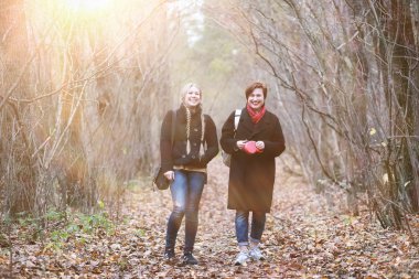Anne ve genç kız sonbahar bahçesinde yürüyüşe çıktılar.