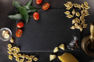 Siyah taş üzerine makarna kabukları. Allspi ile domates ve defne yaprağı