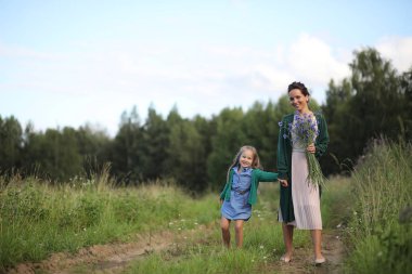 Anne ve kızı yolda yürüyor.
