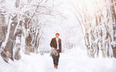 Parkta yürüyen bir adam. Genç adam kışın karla kaplı