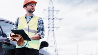 Kasklı ve üniformalı bir adam, sahada bir elektrikçi. Profesör.